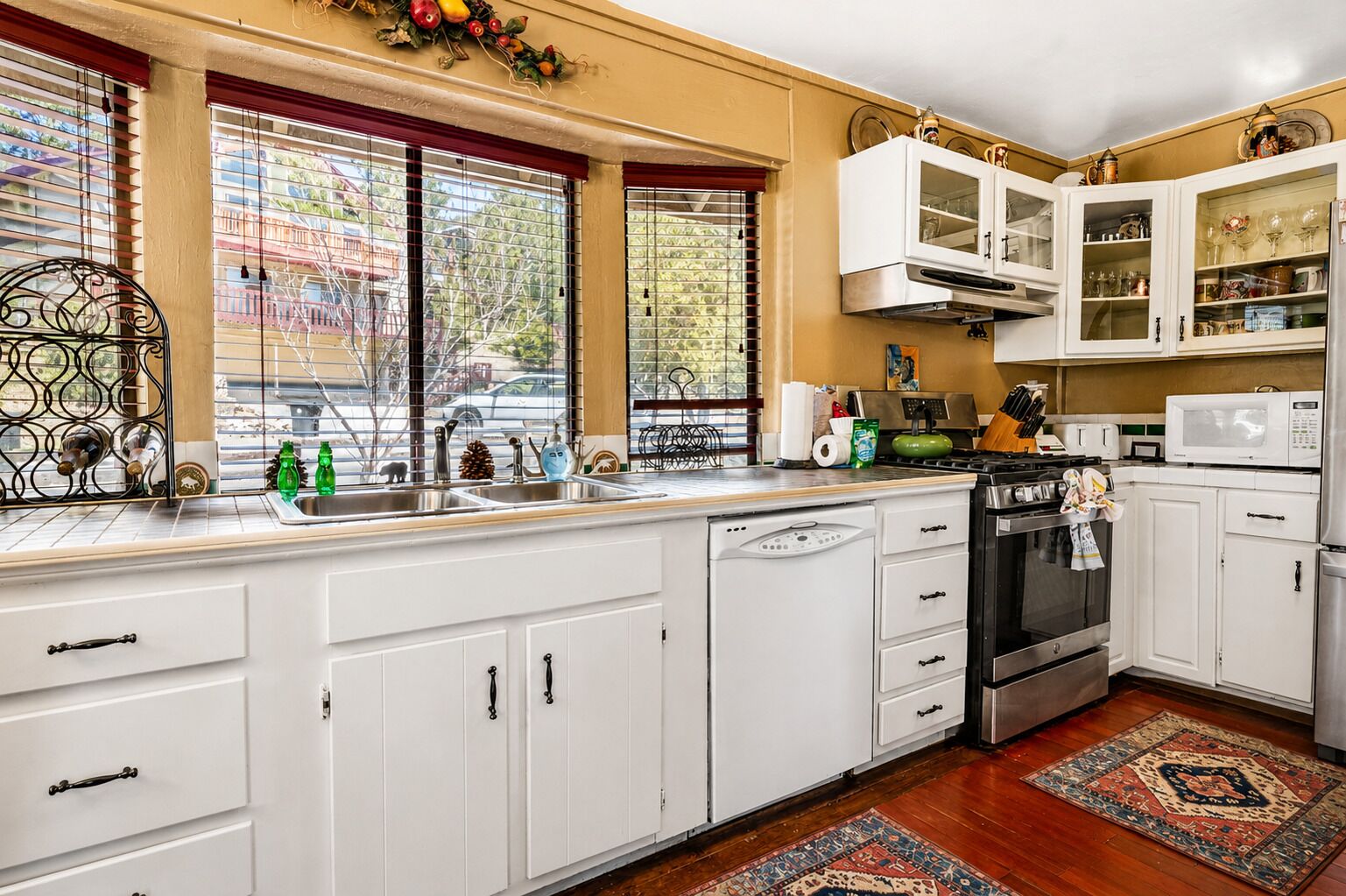 A kitchen with white cabinets, a stove, a microwave, and a sink.