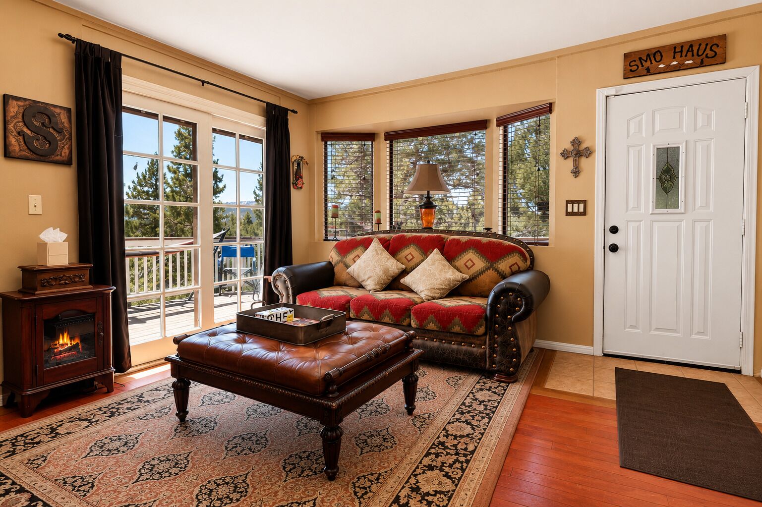 A cozy living room with a fireplace, a leather sofa, and a patterned rug.
