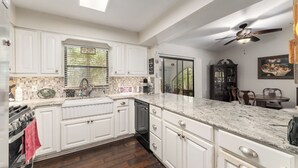 A kitchen with white cabinets, a dishwasher, and a large window. - STUNNING WATERFRONT RETREAT!!! (Lake Panasoffkee)