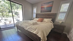 A bedroom with a large bed, a wooden headboard, a nightstand, and a painting on the wall. - STUNNING WATERFRONT RETREAT!!! (Lake Panasoffkee)