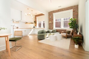 A modern living room with a green sofa, wooden coffee table, and a dining area with a wooden table and chairs. - Airy Midcentury Loft Apartment in SoMa (Little Rock)