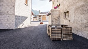 Una stretta via fiancheggiata da edifici, un tavolino in vimini con un vaso e una panchina in legno.