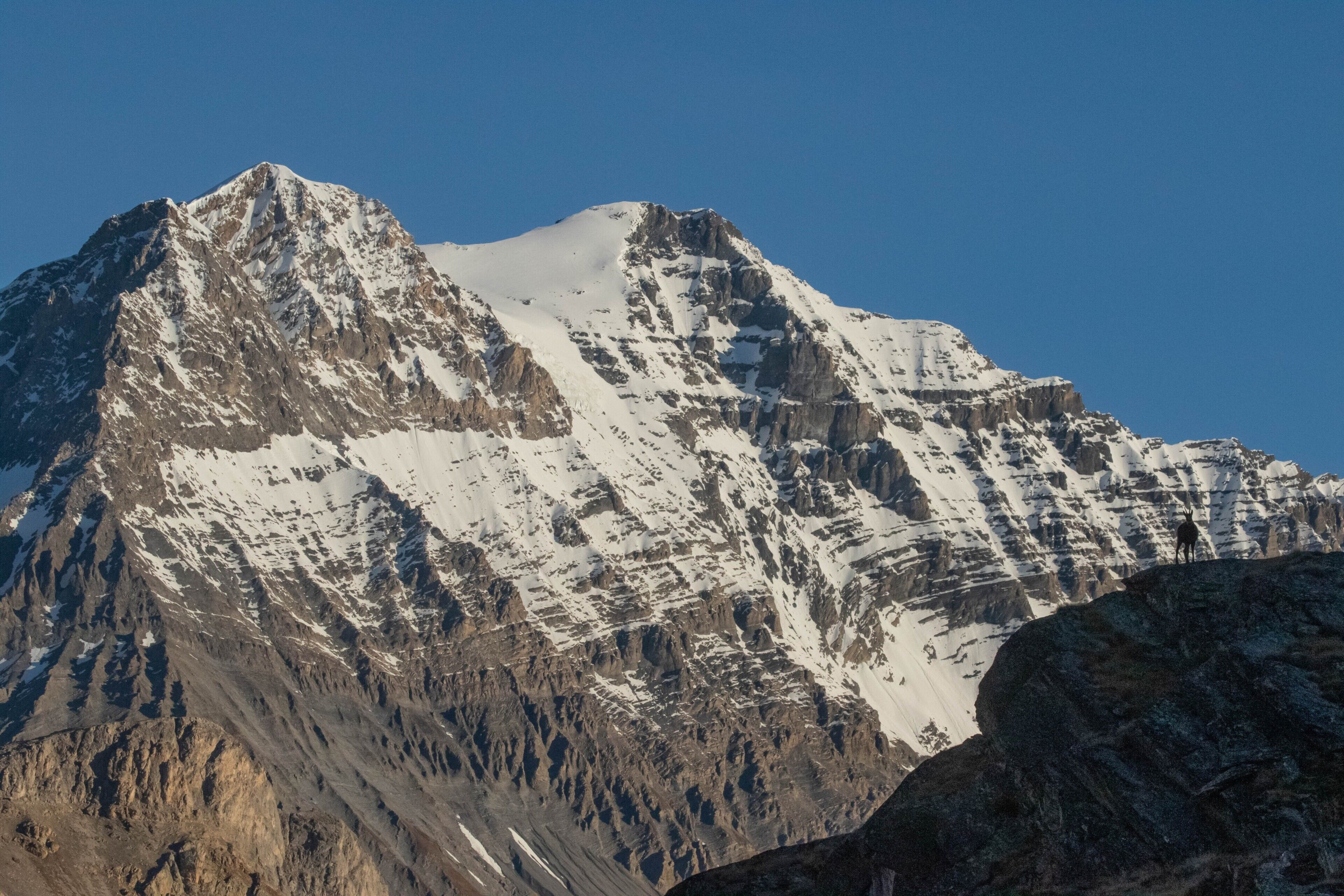 A mountain with snow-covered peaks and rocky terrain.