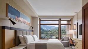 A bedroom with a large bed, a desk, a chair, and a view of mountains through the window. - Fabulous luxury resort hotel suite in delightful Avon w/ AC, WiFi, fitness, pool (Avon)