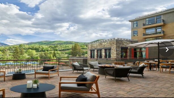 An outdoor patio with seating and tables, overlooking a mountainous landscape. - Fabulous luxury resort hotel suite in delightful Avon w/ AC, WiFi, fitness, pool (Avon)