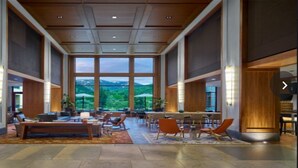 A spacious lobby with a high ceiling, large windows offering a view of the outdoors, and a variety of seating arrangements. - Fabulous luxury resort hotel suite in delightful Avon w/ AC, WiFi, fitness, pool (Avon)
