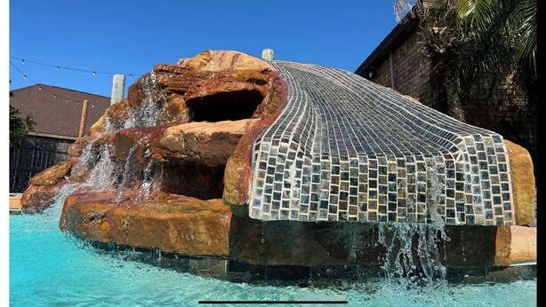 A water feature with a tiled waterfall and a rock formation. - Backyard Oasis in Brownsville! (Brownsville)
