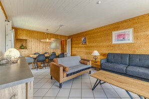 Un interior de madera con un sofá, una mesa de comedor con sillas y una lámpara.
