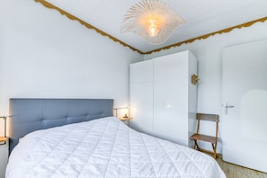 Un dormitorio con cama, lámparas de noche, armario y una silla.