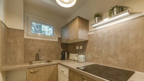 A kitchen with a dishwasher, a toaster, a kettle, a built-in oven, and a window above the sink.