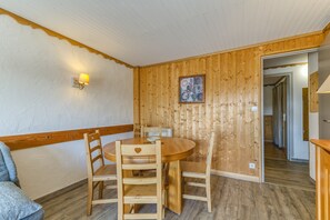 Una habitación con pared de madera, una mesa redonda con sillas, una lámpara y un cuadro enmarcado.