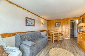 Una habitación acogedora con un sofá gris, una mesa de comedor de madera y sillas.