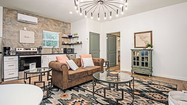 A modern living room with a brown sofa, a glass coffee table, and a patterned rug.