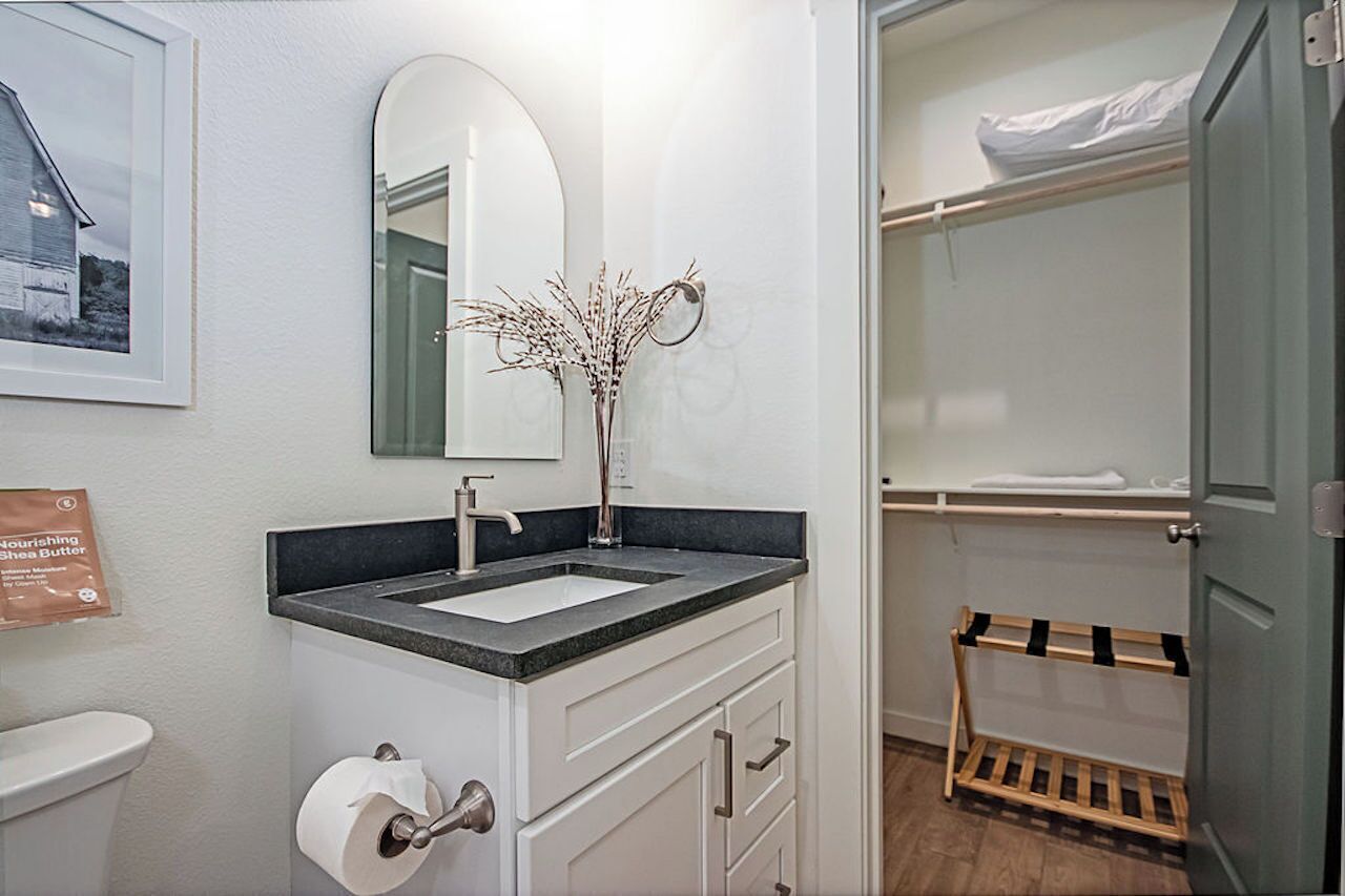 Une salle de bain équipée d’un lavabo, d’un miroir, de toilettes et d’un porte-serviettes.
