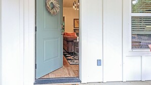 A door with a wreath, a rug, and a chair inside.
