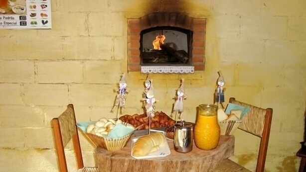 A rustic wooden table with a brick oven, surrounded by wicker chairs.
