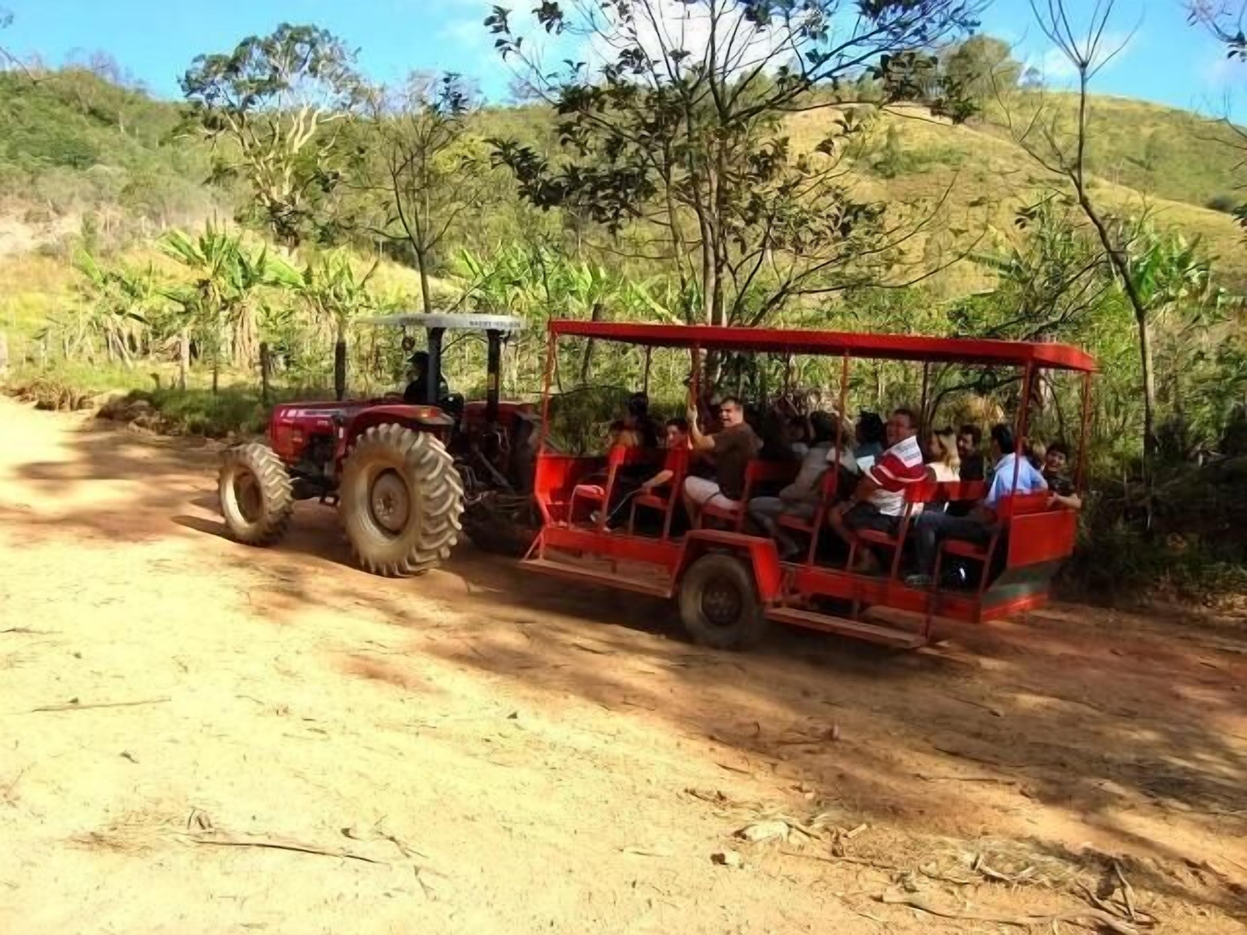 A red tractor pulling a cart with passengers.