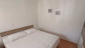 Une chambre à coucher avec une tête de lit en bois, un lit blanc et une table de chevet.