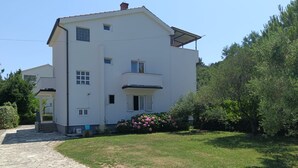 Un bâtiment à deux étages, doté d’un toit plat, d’une entrée bien visible et d’un petit jardin agrémenté de fleurs roses.