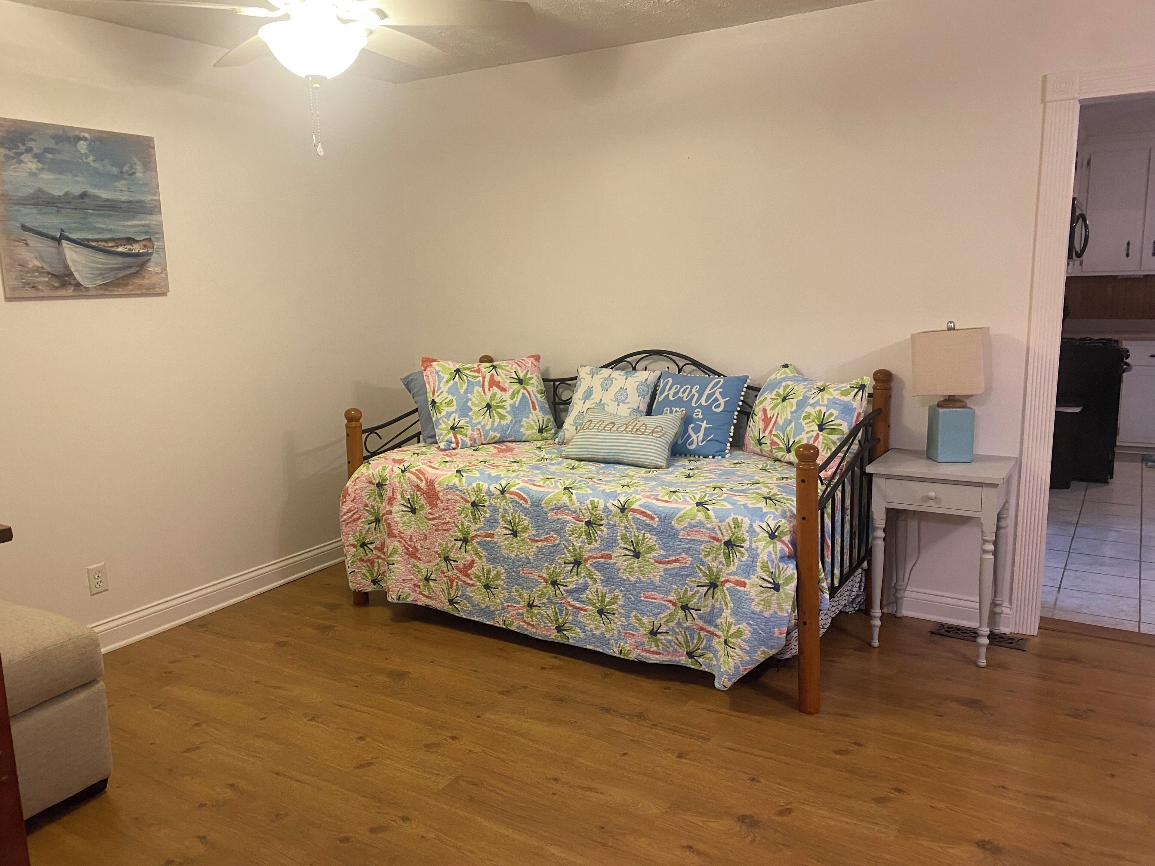 A bedroom with a bed, a nightstand, a lamp, and a painting on the wall.