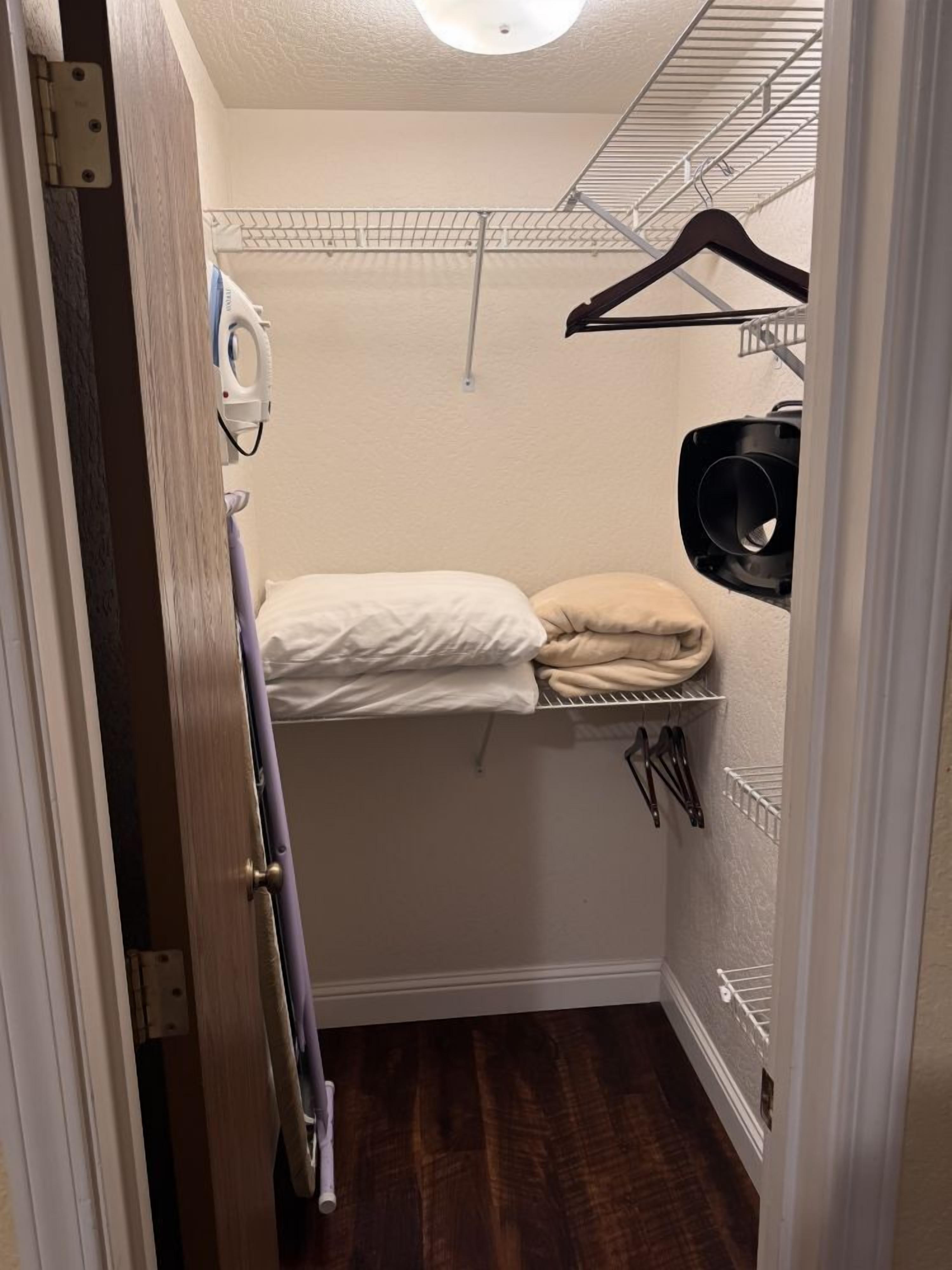 Um roupeiro pequeno com cama, cabideiro e radiador.