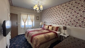 Une chambre à coucher avec un grand lit, une télévision, un bureau et un papier peint à motifs.