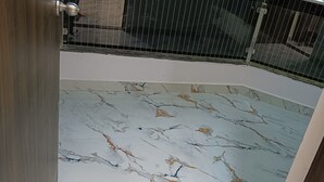 A room with a marble floor, a metal railing, and a view of the outside.
