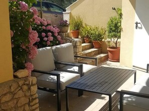 A patio with a sofa and table, surrounded by potted plants and a stone wall. - Apartments Ivan Supetar (Supetar)
