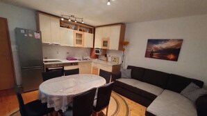 A compact living space with a kitchenette, a dining table with chairs, a sofa, and a painting on the wall. - Apartments Ivan Supetar (Supetar)