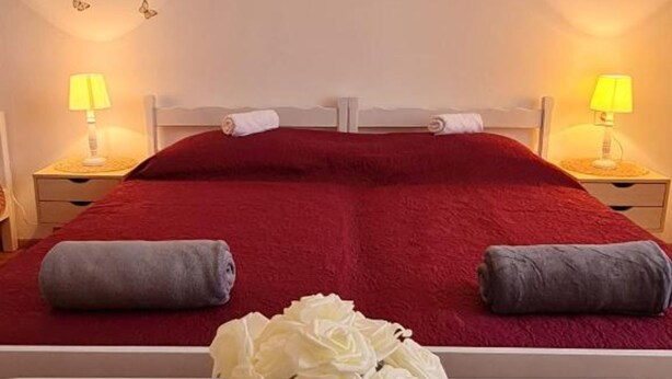 A double bed with red bedding, two bedside lamps, and a vase of white flowers. - Apartment Bijonda Near Arena Pula (Pula)