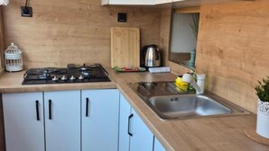 A modern kitchen with white cabinets, a gas stove, a sink, and a wooden countertop. - Apartment Bijonda Near Arena Pula (Pula)