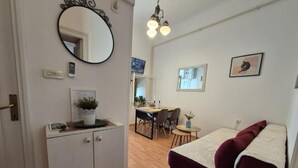 A compact room with a bed, a desk, and a chair. There is a mirror on the wall, a small table with a plant, and a light fixture above the desk. - Apartment Bijonda Near Arena Pula (Pula)