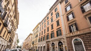A street view of a row of historic buildings with multiple stories, featuring balconies, arched doorways, and a variety of architectural details. - GUEST HOUSE GOITO (Rome)