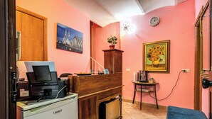 A compact room with a desk, a printer, a small cabinet, a blue sofa, a clock, and a painting on the wall. - GUEST HOUSE GOITO (Rome)