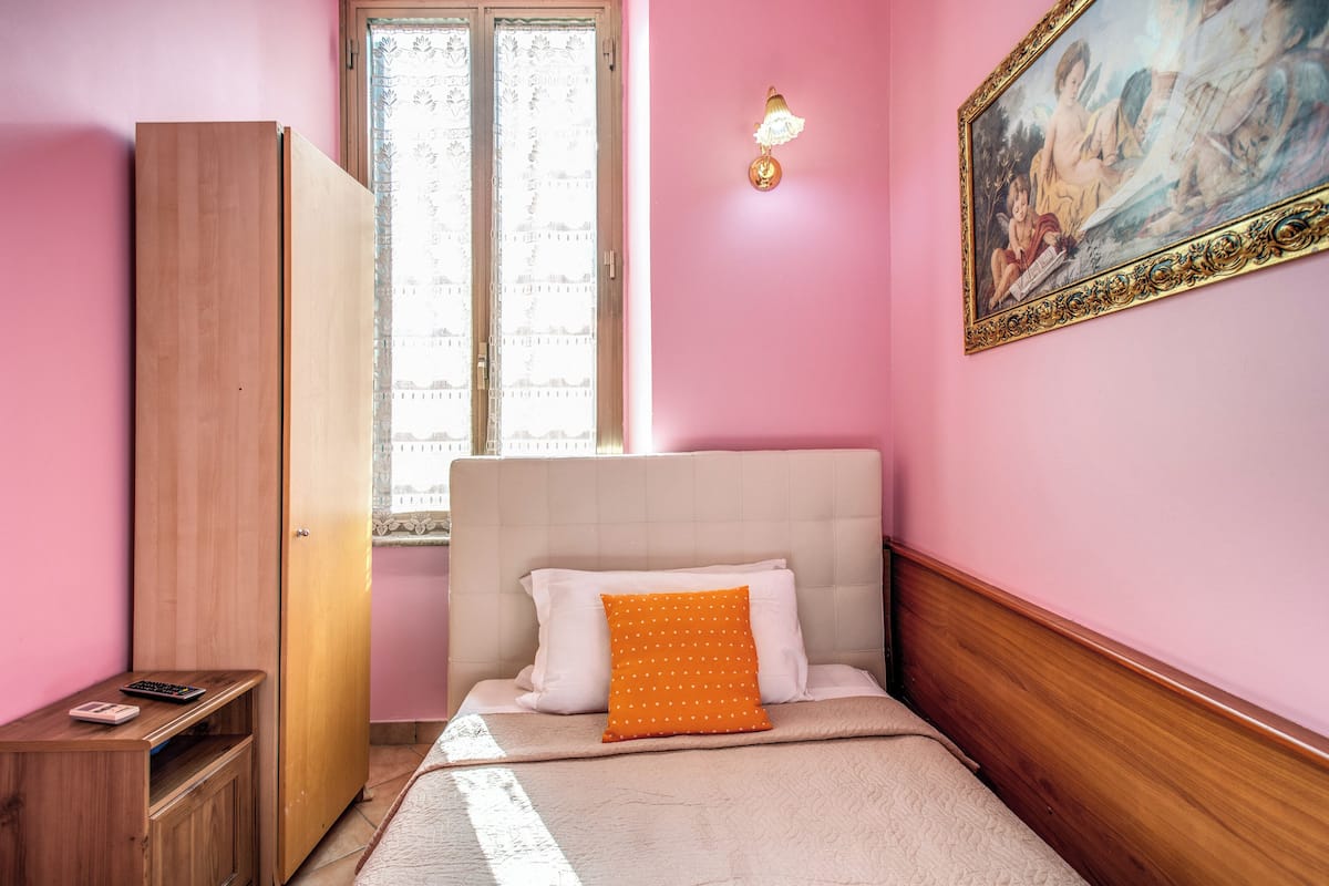 Ein Schlafzimmer mit Bett, Kleiderschrank, Schreibtisch und Fenster.