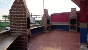 A patio with brick-built outdoor ovens, a metal railing, and a red and blue wall. - Hotel Las Vegas (Matamoros)