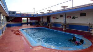 A swimming pool area with a pool, lounge chairs, and a sign for 'Hotel Las Vegas'. - Hotel Las Vegas (Matamoros)