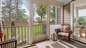 Une véranda donnant sur le jardin, avec une chaise en osier et une petite table.