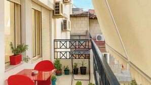 A balcony with red chairs, potted plants, and a metal railing.