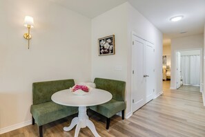 A room with a green sofa, a white table with a vase, a wall-mounted lamp, and a door leading to another room. - Water Oaks Retreat Charming 2-bedroom house in Laurel Hill (Laurel Hill)