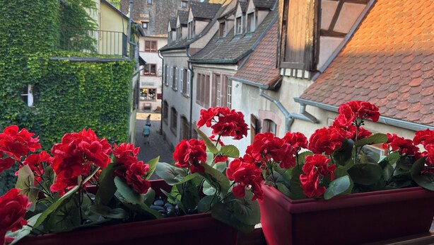 Eine enge Straße mit traditioneller europäischer Architektur, darunter Fachwerkhäuser und ein freistehender Schornstein.