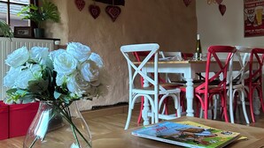 Ein Essbereich mit Holzboden im Fischgrätmuster, einem Tisch mit einer Zeitschrift und Stühlen in Rot und Weiß.