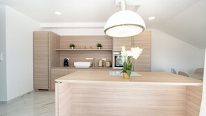 A modern kitchen with a central island, wooden cabinetry, and a pendant light.