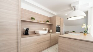 A modern kitchen with light wood cabinetry, a white countertop, and a built-in oven.