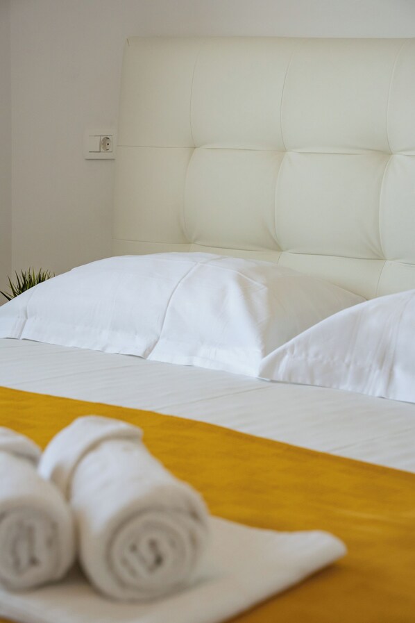A neatly made bed with white linens and rolled towels on a yellow bedspread. - Dominik  (Mandre)
