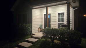 Une maison avec un porche, des marches menant à la porte et un petit jardin.