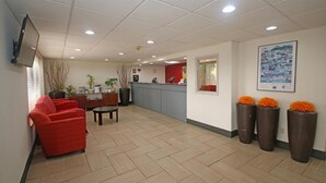 A reception area with a counter, chairs, and a large potted plant. - Knights Inn Pilot Mountain (Pilot Mountain)