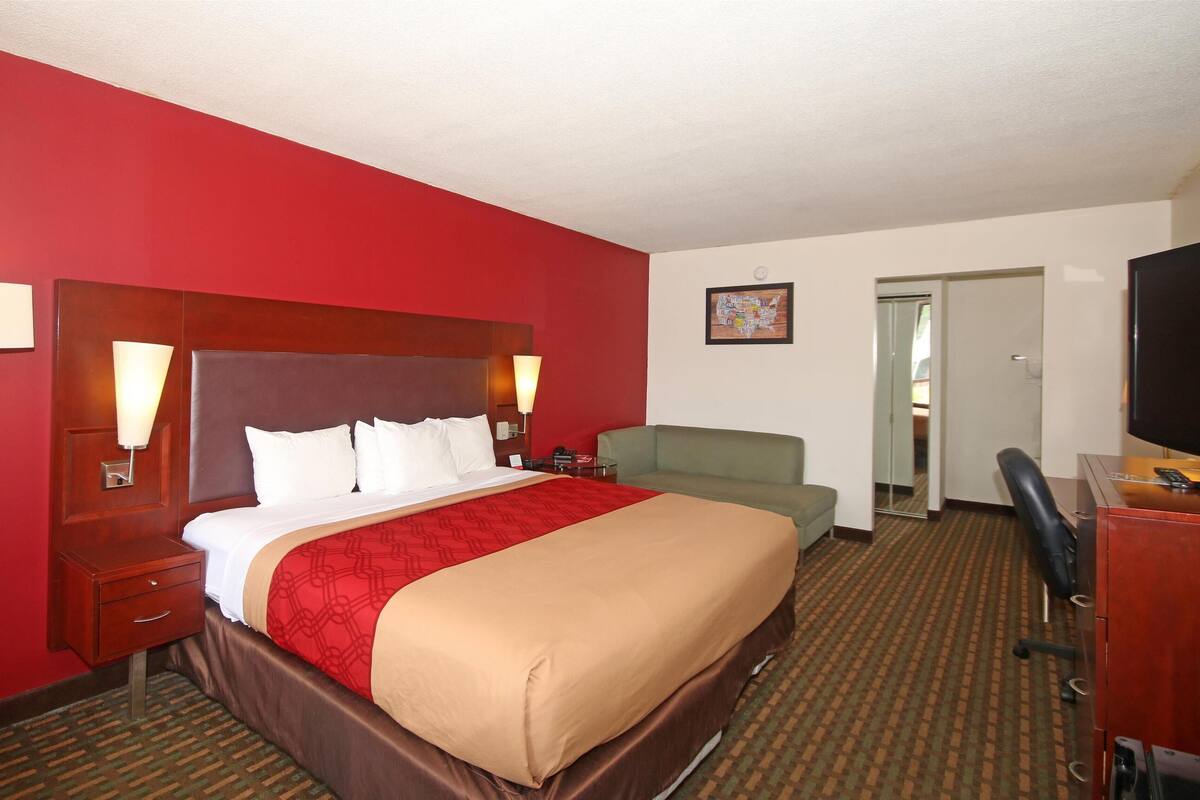 Une chambre d’hôtel avec un grand lit, un bureau, une chaise et un téléviseur.