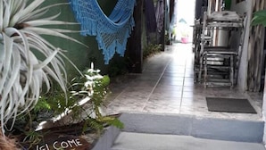 A narrow alleyway with a wooden staircase leading up, a hammock hanging on the wall, and a welcome sign at the bottom. - Guest House Peace Love (Porto Seguro)