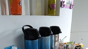 A kitchen counter with a milk carton, three thermos flasks, and a plate. - Guest House Peace Love (Porto Seguro)